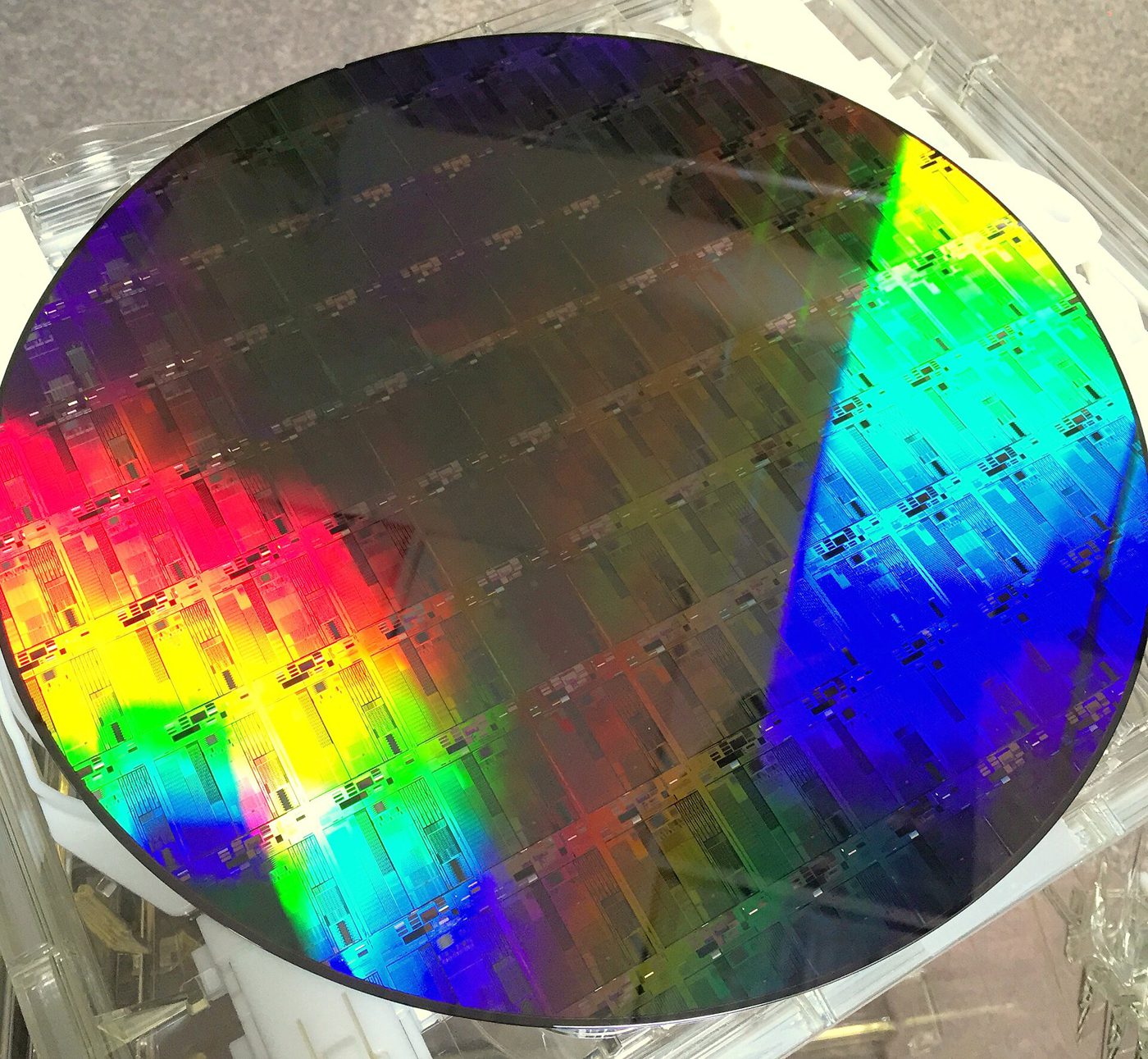 A 300mm silicon photonics wafer reflecting rainbow colours, with a grid of chips